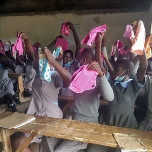 Junge Mädchen in Afrika freuen sich über die Übergabe von wiederverwendbaren Binden