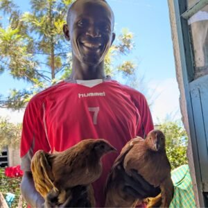 Mitarbeiter von Go Fishnet übergibt zwei Hühner als Spendengeschenk